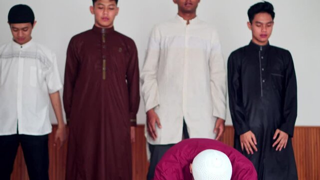 Group Of Muslim Young Friends Kneeling Doing Ruku And Prostration Pose Praying Salah Together At The Mosque