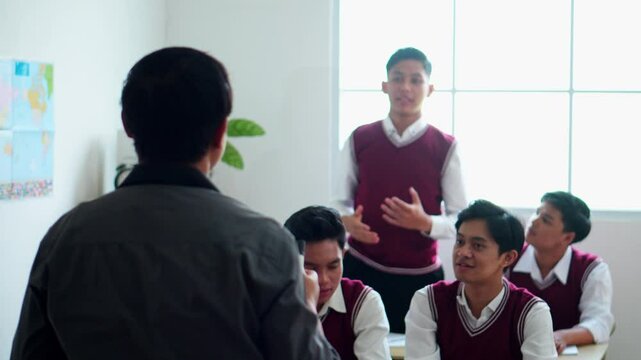 Back View Of Teacher Teaching Students While The Student Rising Hands For Asking Or Answering
