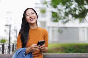 Smiling young woman using smartphone outdoors in urban setting