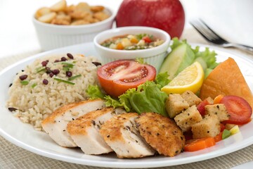 Plate of food with a chicken, rice, and vegetables