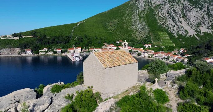 Flying By St. Michael Church, Revealing Bay With Docked Catamaran Boat And Cruise Ship. Trstenik, Peljesac Peninsula, Croatia. drone shot