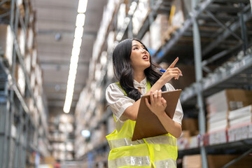 Asian warehouse staff woman checking inventory with clipboard in logistics management, working in...