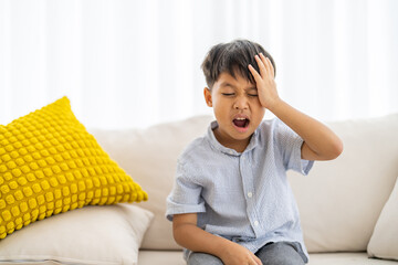 Portrait of sick depressed unhappy child boy touching on head feel suffering head ache pain flu...