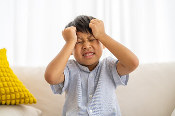 Portrait of sick depressed unhappy child boy touching on head feel suffering head ache pain flu...