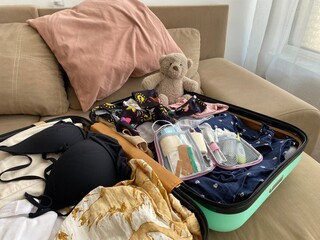 Open first aid kit placed among mixed family clothes, including swimwear and casual outfits. A...