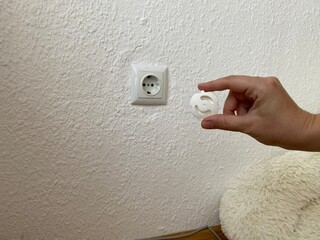 Demonstration of childproof socket covers being inserted into a power outlet to prevent accidental...
