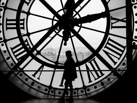 A human figure in silhouette stands out against a large clock, Paris, France, in black and white