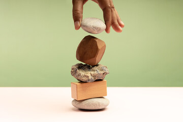 A hand dropping a pebble rock on unstable Stone Stack, symbolizing fragile financial stability and economic uncertainty