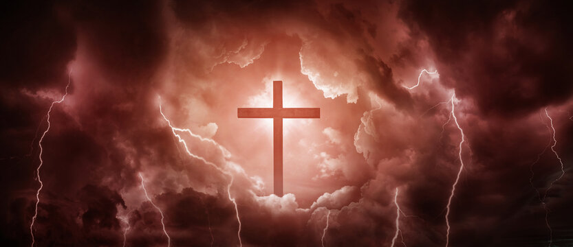 The silhouete of the cross and sunlight as a symbol of the Christian faith and a stormy sky with lightnings as a symbol of mortal life full of trials. Concept on the theme of God, paradise, religion.