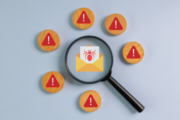 Magnifying glass focusing on warning email with virus icon, surrounded by red alert signs,...
