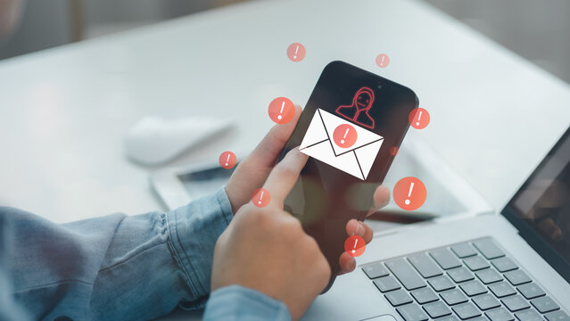 Hand holding smartphone with warning signs and phishing email icon on screen, representing mobile security threat, email scam, identity theft, digital fraud, and online privacy protection.