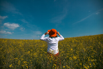 Trendy woman with stylish hat feeling free in the field with flowers