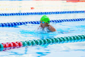 Swimmer child swims breaststroke swimming style in a race swimming pool. Water sports and...