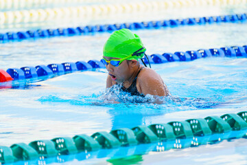 Swimmer child swims breaststroke swimming style in a race swimming pool. Water sports and...