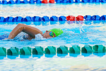 Swimmer child swims freestyle swimming style in a race swimming pool. Water sports and competition,...