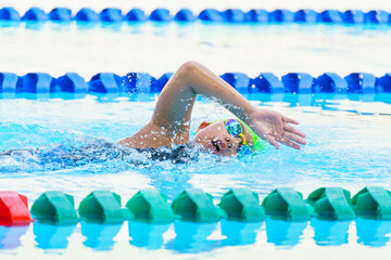 Swimmer child swims freestyle swimming style in a race swimming pool. Water sports and competition,...