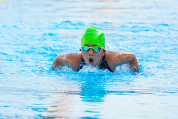 Swimmer child swims butterfly swimming style in a race swimming pool. Water sports and competition,...