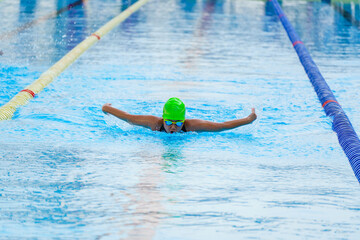 Swimmer child swims butterfly swimming style in a race swimming pool. Water sports and competition,...