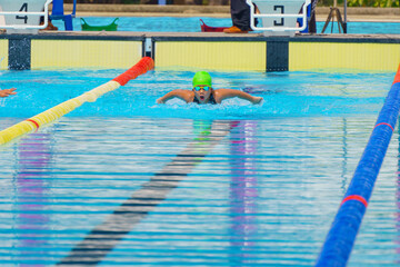 Swimmer child swims butterfly swimming style in a race swimming pool. Water sports and competition,...