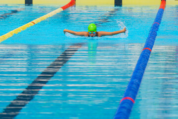 Swimmer child swims butterfly swimming style in a race swimming pool. Water sports and competition,...