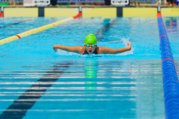 Swimmer child swims butterfly swimming style in a race swimming pool. Water sports and competition,...