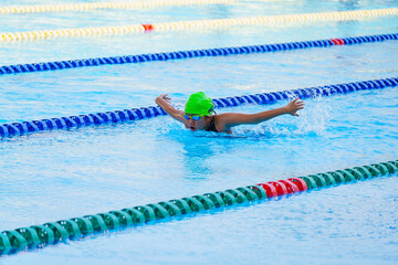 Swimmer child swims butterfly swimming style in a race swimming pool. Water sports and competition,...