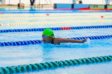 Swimmer child swims butterfly swimming style in a race swimming pool. Water sports and competition,...