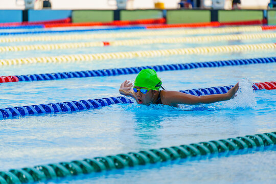 Swimmer child swims butterfly swimming style in a race swimming pool. Water sports and competition, learning to swim classes for children.