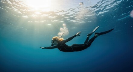 Freediver swims in the deep blue sea with sunlight and bubbles