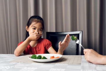 Little cute kid girl refusing to eat healthy vegetables. Children do not like to eat vegetables.