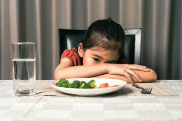 Little cute kid girl refusing to eat healthy vegetables. Children do not like to eat vegetables.