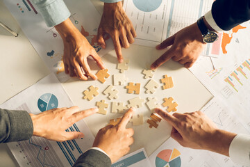 The concept of teamwork and partnership. Businessman's hands putting together puzzle pieces in the office and join together in a jigsaw puzzle team. Charity. Volunteers. Business unity as a team.
