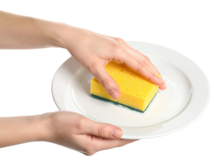 Two hands hold a white plate while one hand cleans it with a yellow and green sponge.