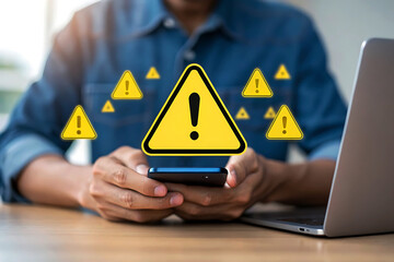 Man with smartphone and laptop surrounded by glowing yellow warning signs
