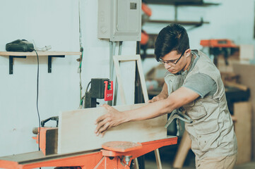 Young carpenter edging wood in the workshop
