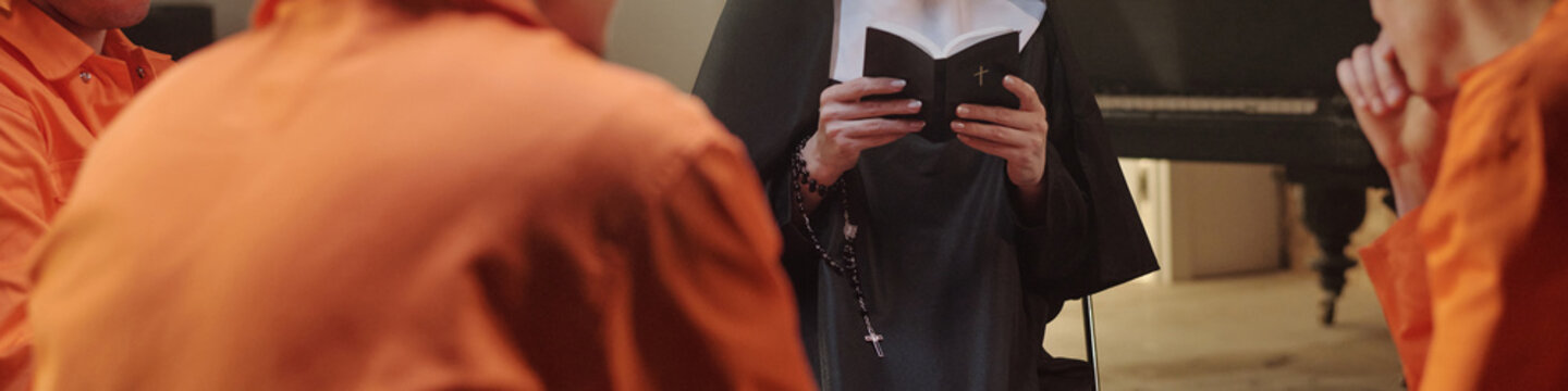 Nun reading book to group of young adult men in orange prison uniforms, inmates sitting and listening attentively in prison library setting