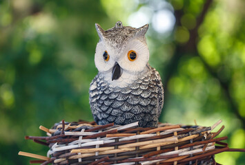 A small owl figurine is sitting on a nest made of twigs