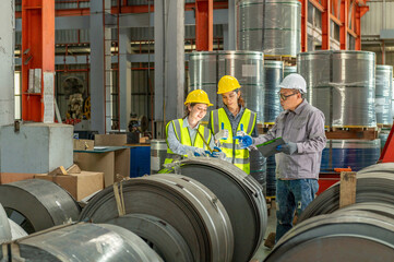 Industrial workers in protective helmets and safety vests discussing construction plans in a...
