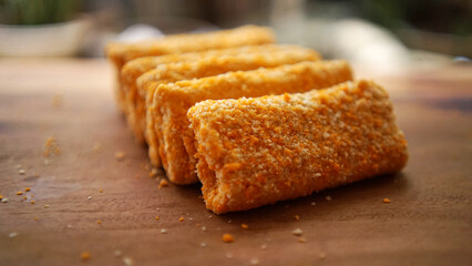 Jakarta, 30 June 2025 : Frozen breaded spring rolls with kaffir lime leaves on wooden background....