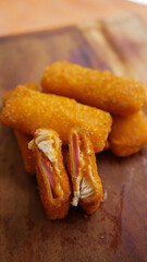 Jakarta, 30 June 2025 : Frozen breaded spring rolls with kaffir lime leaves on wooden background....