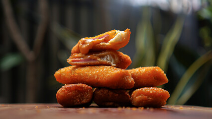 Jakarta, 30 June 2025 : Frozen breaded spring rolls with kaffir lime leaves on wooden background....