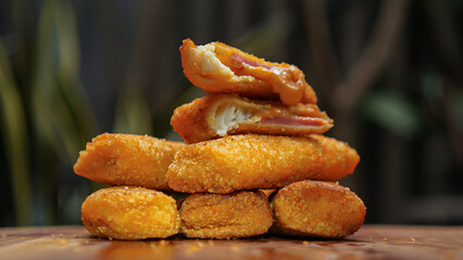 Jakarta, 30 June 2025 : Frozen breaded spring rolls with kaffir lime leaves on wooden background....