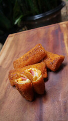 Jakarta, 30 June 2025 : Frozen breaded spring rolls with kaffir lime leaves on wooden background. Raw snack food ready to cook