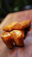 Jakarta, 30 June 2025 : Frozen breaded spring rolls with kaffir lime leaves on wooden background....