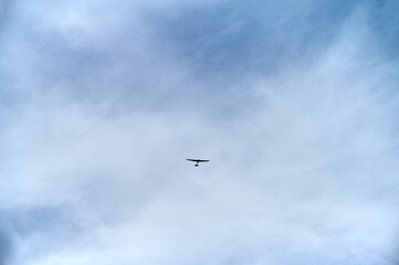 A small airplane glides through the clear sky, surrounded by soft clouds on a calm afternoon.