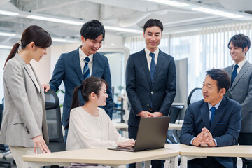 チームメンバーで非常ににこやかに仕事をするオフィスワーカー