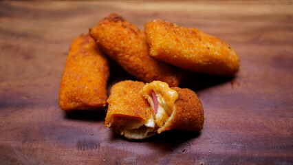 Jakarta, 30 June 2025 : Frozen breaded spring rolls with kaffir lime leaves on wooden background. Raw snack food ready to cook