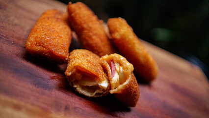 Jakarta, 30 June 2025 : Frozen breaded spring rolls with kaffir lime leaves on wooden background. Raw snack food ready to cook