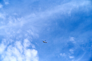 Fototapeta premium A helicopter soars through a clear blue sky, surrounded by light, fluffy clouds, showcasing a vibrant day.