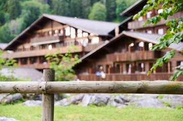 Visitors enjoy the peaceful atmosphere near charming wooden chalets surrounded by vibrant nature in summer.